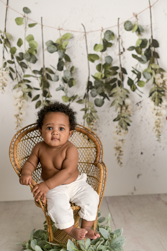 baby boy sitting in the wicker chair smiling with flower vintage background